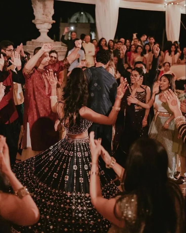 Bride twirling her lehenga as guests clap around her