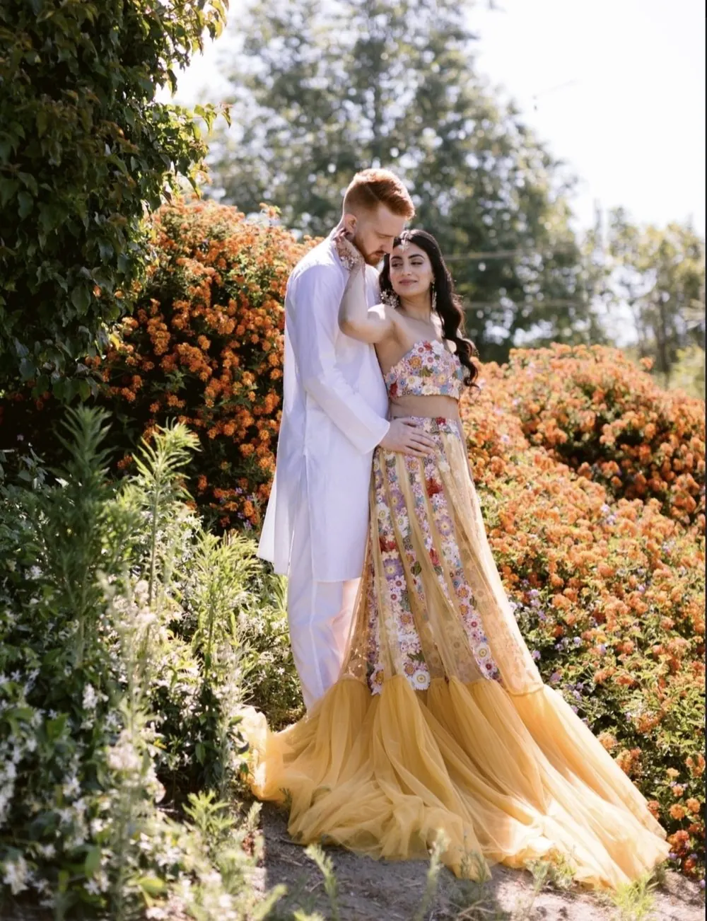 Couple in Mehndi outfits among orange flowers