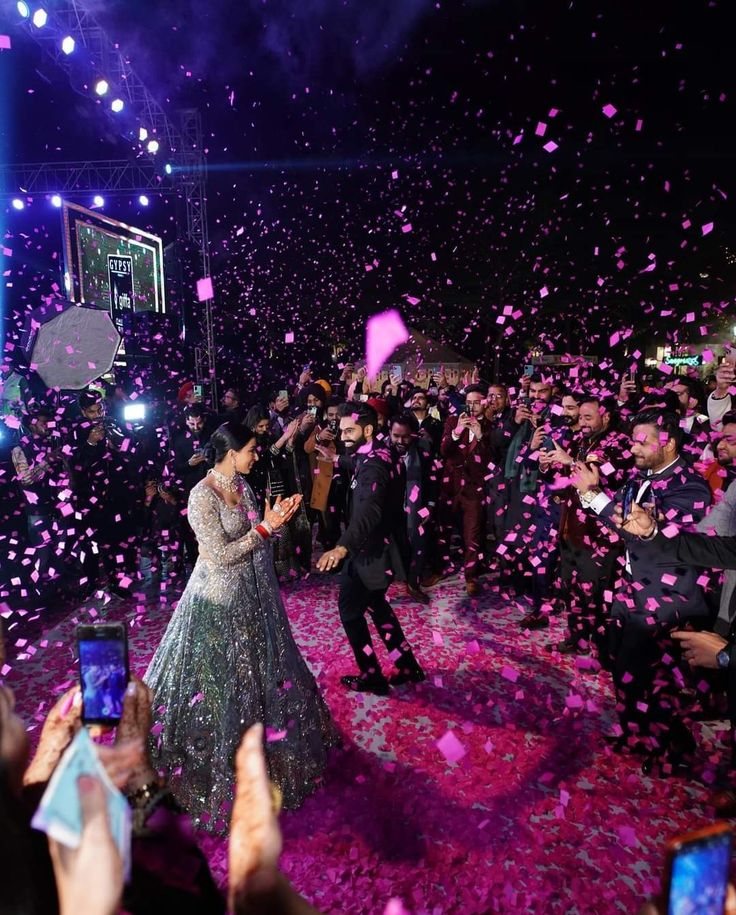 Couple dancing through pink confetti at their Sangeet