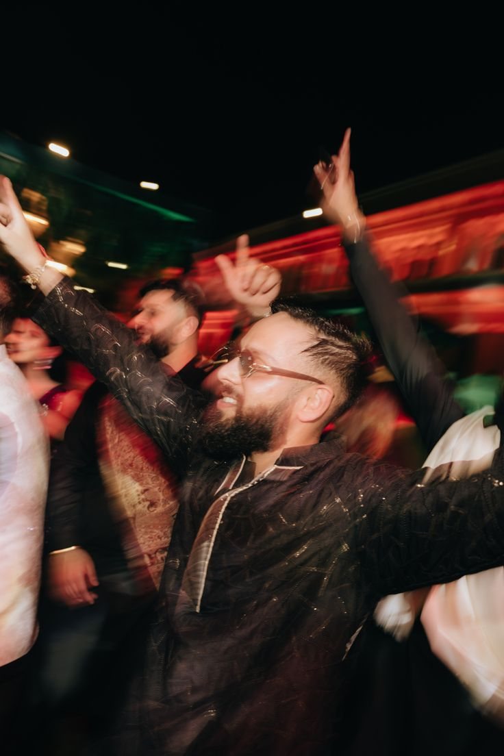 Guest with arms up on a packed Sangeet dance floor