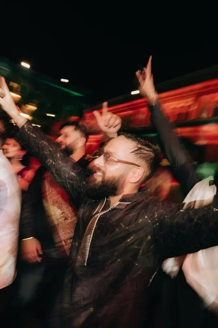 Guest with arms up on a packed Sangeet dance floor