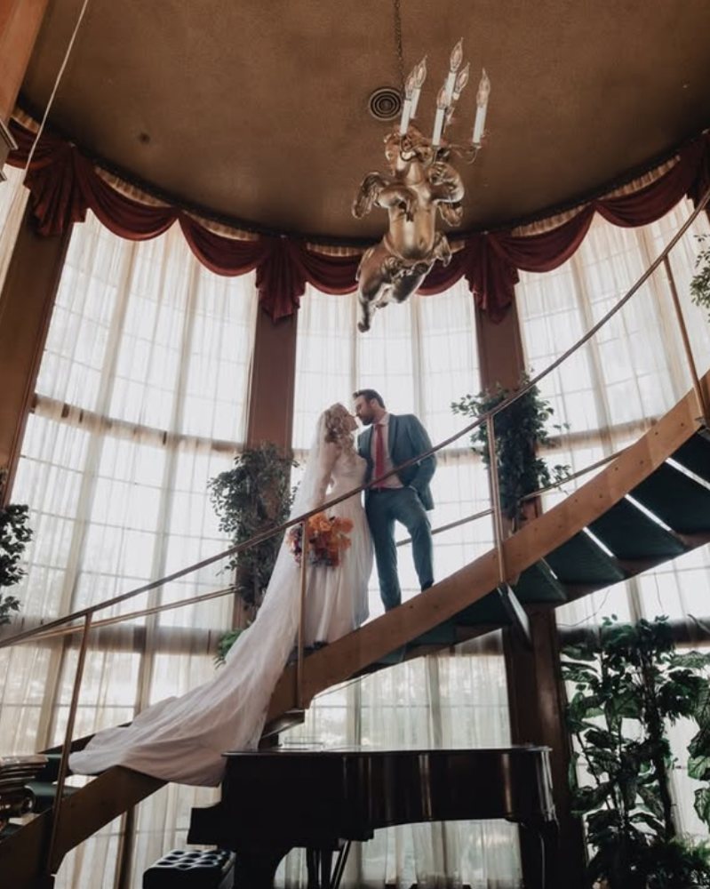 Bride and groom on a spiral staircase beneath a chandelier, photographed by Lulan Photo